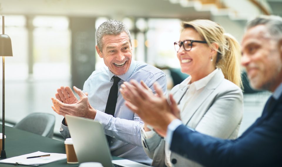Mature businesspeople smiling and clapping during an office presentation
